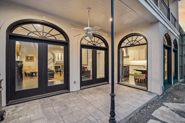 property entrance featuring a patio, french doors, a ceiling fan, and stucco siding