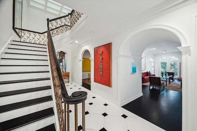 staircase featuring arched walkways, ornamental molding, baseboards, and recessed lighting