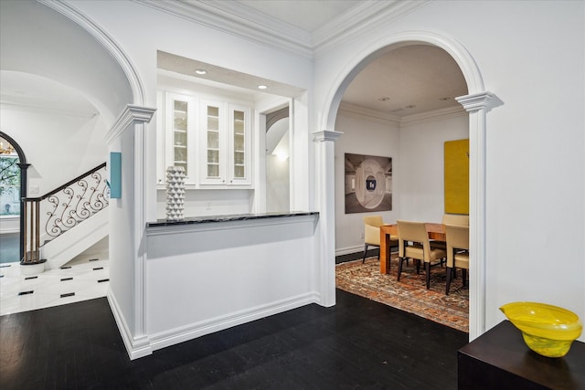 kitchen with arched walkways, crown molding, decorative columns, glass insert cabinets, and white cabinetry