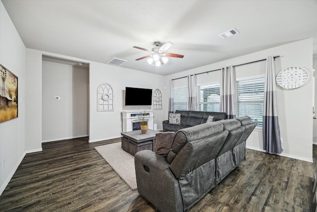 living room featuring ceiling fan, visible vents, dark wood finished floors, and baseboards