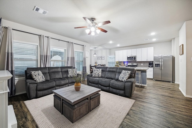 living area with ceiling fan, visible vents, dark wood finished floors, and baseboards