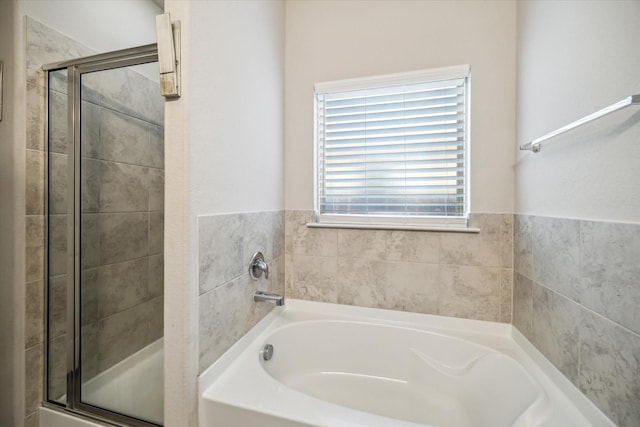 bathroom featuring a stall shower and a bath