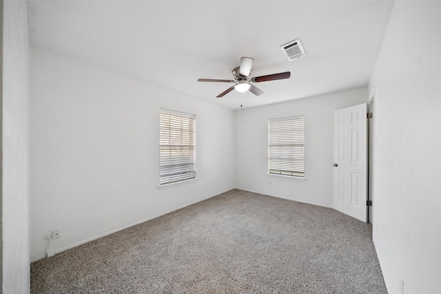 carpeted empty room with visible vents and a ceiling fan