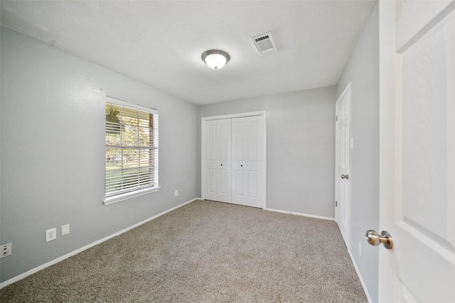 unfurnished bedroom featuring carpet floors, a closet, visible vents, and baseboards