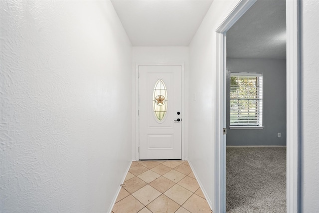 doorway to outside featuring baseboards, light colored carpet, and light tile patterned flooring