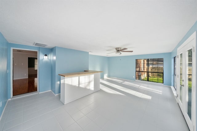 tiled empty room featuring a ceiling fan, visible vents, and baseboards