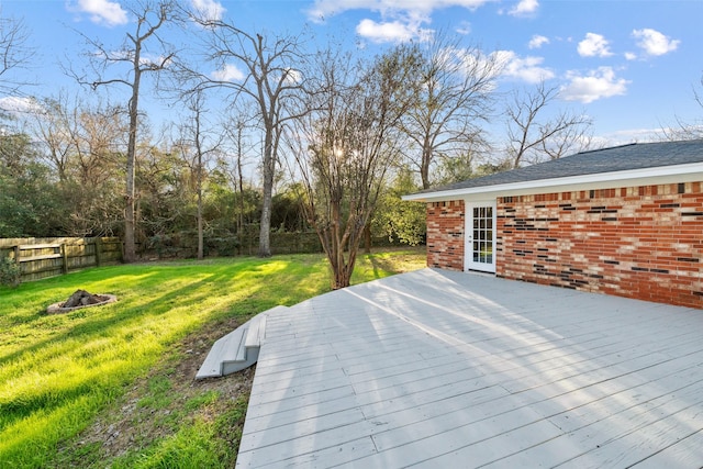 wooden deck featuring an outdoor fire pit, a lawn, and fence