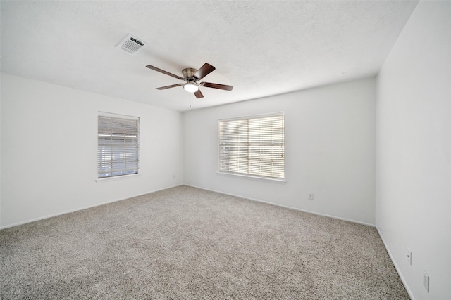 carpeted empty room with a textured ceiling, ceiling fan, and visible vents