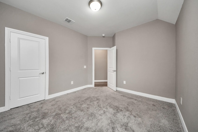 empty room featuring vaulted ceiling, carpet flooring, visible vents, and baseboards