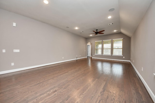 empty room with arched walkways, visible vents, dark wood-type flooring, a ceiling fan, and baseboards