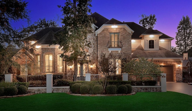 view of front of property with a fenced front yard, a front yard, brick siding, and a balcony