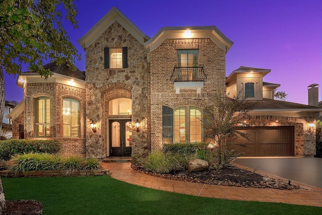 view of front of house with concrete driveway, a balcony, stone siding, french doors, and brick siding