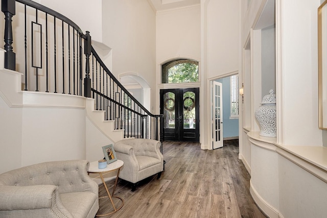 entrance foyer featuring baseboards, stairway, wood finished floors, a high ceiling, and french doors