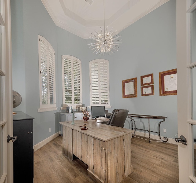 office area featuring baseboards, an inviting chandelier, a tray ceiling, crown molding, and light wood-style floors