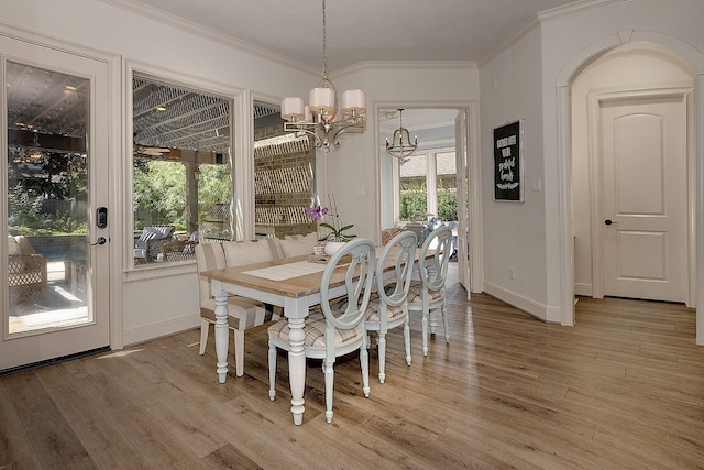 dining area featuring a chandelier, light wood-type flooring, and crown molding