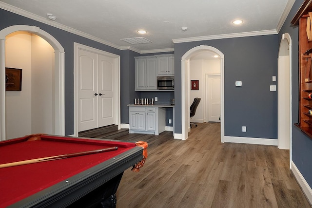 recreation room featuring ornamental molding, arched walkways, visible vents, and wood finished floors