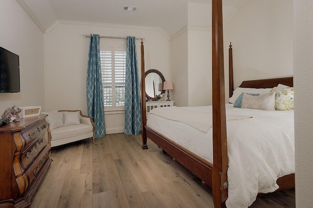 bedroom with visible vents, vaulted ceiling, crown molding, and wood finished floors