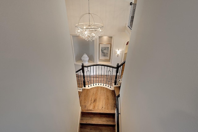 staircase with wood finished floors and a notable chandelier