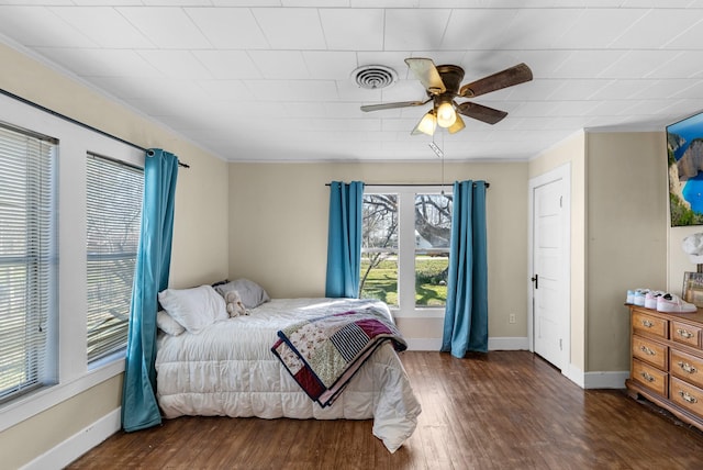 bedroom featuring a ceiling fan, wood finished floors, visible vents, and baseboards