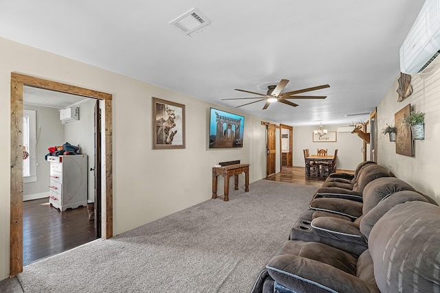 living area featuring carpet, ceiling fan with notable chandelier, visible vents, and a wall mounted AC