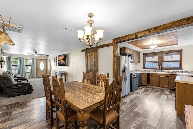 dining area featuring a notable chandelier, visible vents, a tray ceiling, and wood finished floors