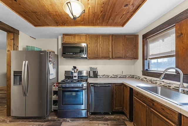 kitchen featuring tasteful backsplash, dark wood-type flooring, wood ceiling, appliances with stainless steel finishes, and a sink