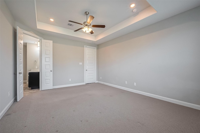 unfurnished bedroom with recessed lighting, carpet flooring, visible vents, baseboards, and a raised ceiling