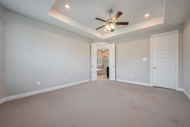 unfurnished bedroom with baseboards, a raised ceiling, connected bathroom, carpet, and recessed lighting