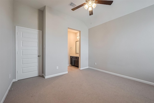 unfurnished bedroom featuring lofted ceiling, connected bathroom, light colored carpet, visible vents, and baseboards