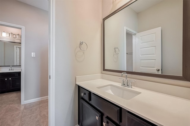 bathroom with baseboards, two vanities, a sink, and tile patterned floors