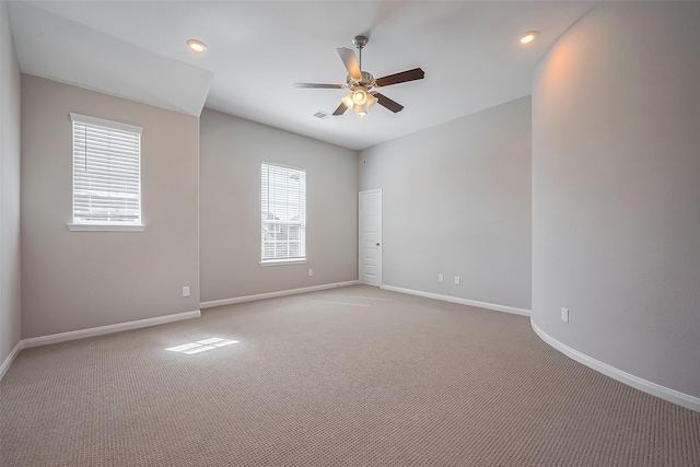 empty room with visible vents, baseboards, a ceiling fan, and light colored carpet