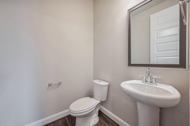 bathroom with toilet, a sink, baseboards, and wood finished floors