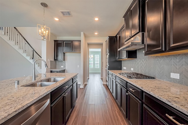 kitchen with visible vents, appliances with stainless steel finishes, a sink, light stone countertops, and under cabinet range hood