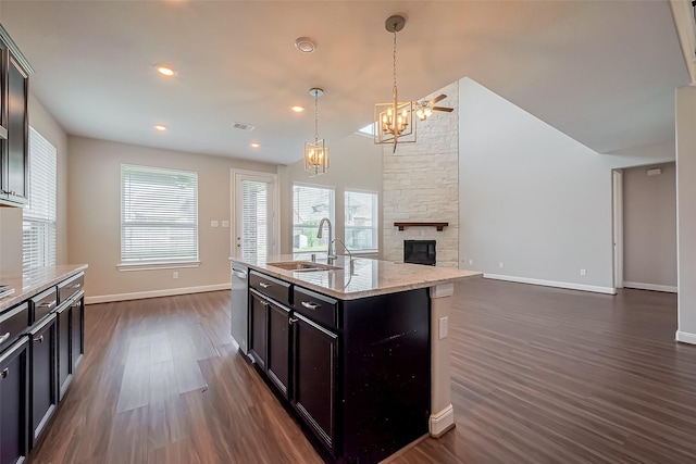 kitchen featuring dark wood-style floors, visible vents, a sink, and a stone fireplace