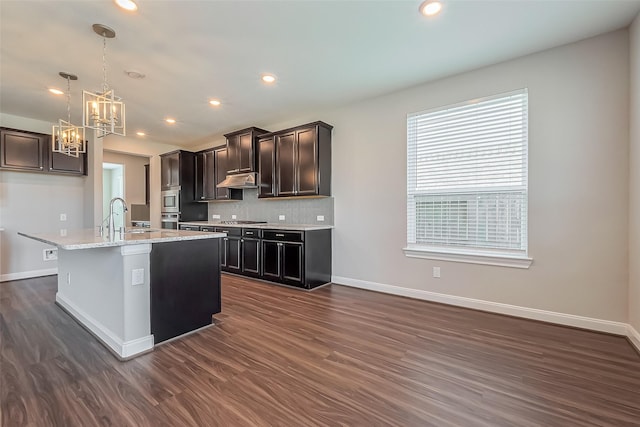 kitchen featuring dark wood finished floors, stainless steel gas cooktop, backsplash, a sink, and baseboards