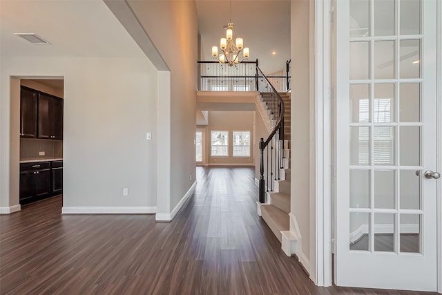 foyer entrance with dark wood finished floors, stairway, baseboards, and an inviting chandelier