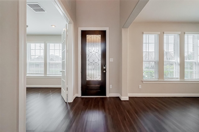 entrance foyer with arched walkways, visible vents, dark wood finished floors, and baseboards