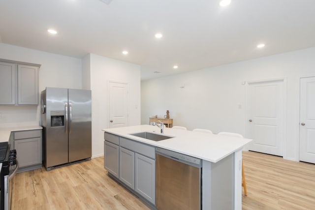 kitchen featuring a sink, stainless steel appliances, gray cabinetry, and light countertops