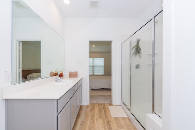 bathroom featuring visible vents, a stall shower, ensuite bathroom, wood finished floors, and vanity