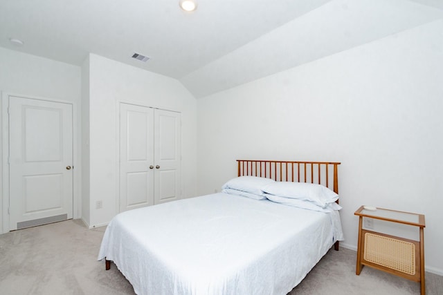 bedroom featuring lofted ceiling, visible vents, a closet, and light carpet