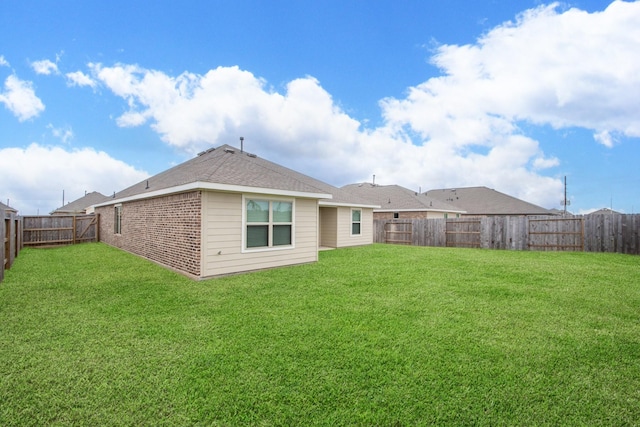 rear view of house featuring a lawn, a fenced backyard, and brick siding