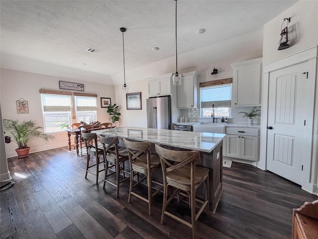 kitchen featuring a breakfast bar area, plenty of natural light, a sink, and freestanding refrigerator