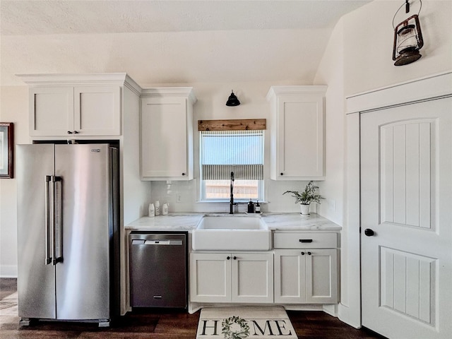 kitchen featuring light stone countertops, white cabinetry, stainless steel appliances, and a sink