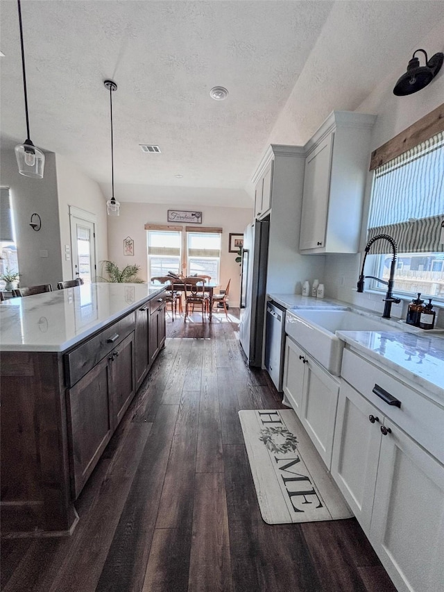 kitchen featuring stainless steel appliances, visible vents, dark wood-type flooring, a sink, and a textured ceiling