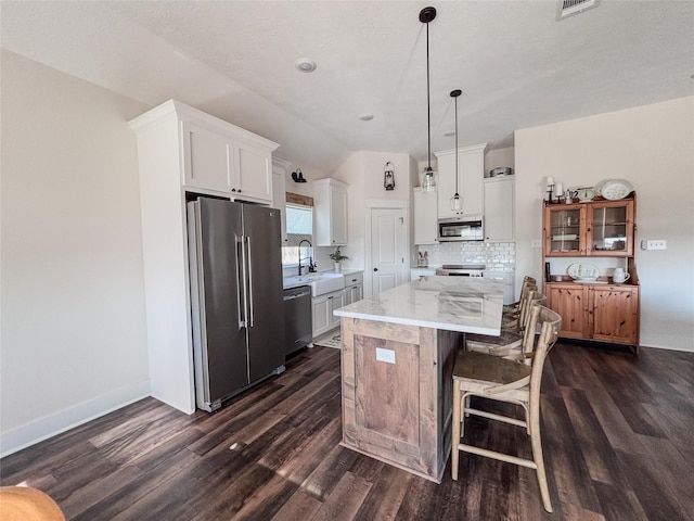 kitchen featuring a breakfast bar area, backsplash, appliances with stainless steel finishes, a kitchen island, and a sink