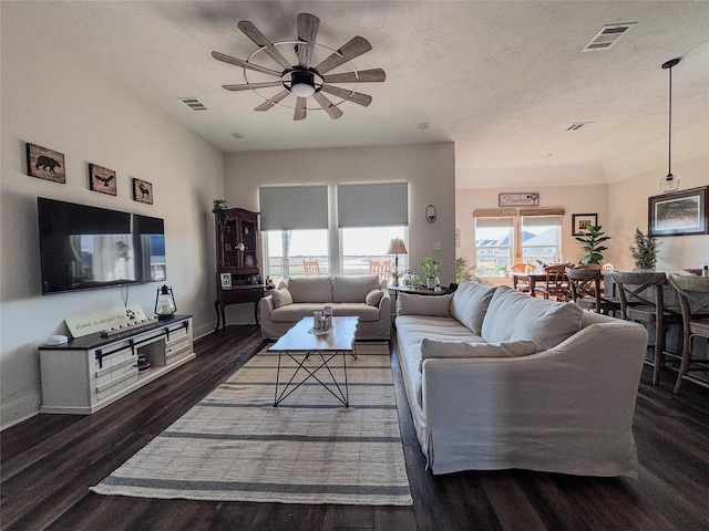 living room featuring a textured ceiling, wood finished floors, visible vents, and a ceiling fan