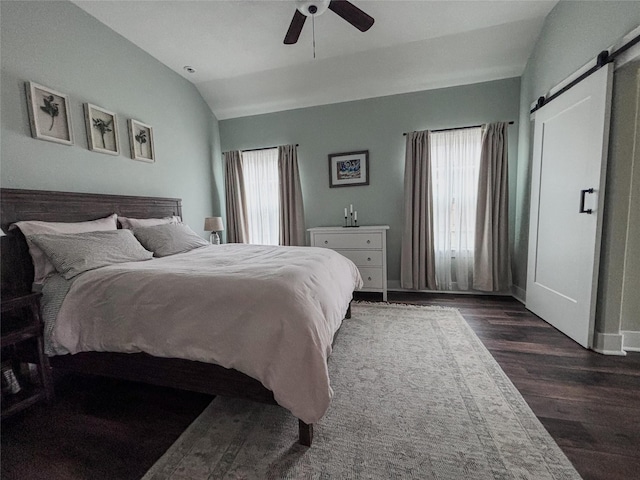 bedroom with lofted ceiling, dark wood-style floors, a barn door, and a ceiling fan