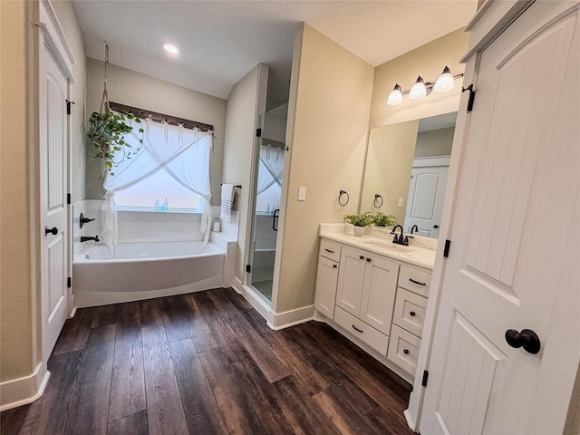 bathroom featuring a garden tub, a stall shower, vanity, wood finished floors, and baseboards