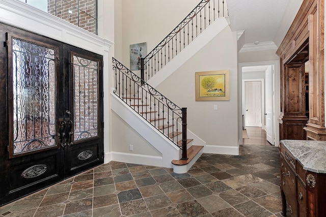 foyer entrance featuring french doors, stone finish flooring, baseboards, and ornamental molding