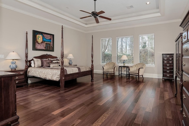 bedroom featuring a tray ceiling, crown molding, dark wood-style flooring, and baseboards